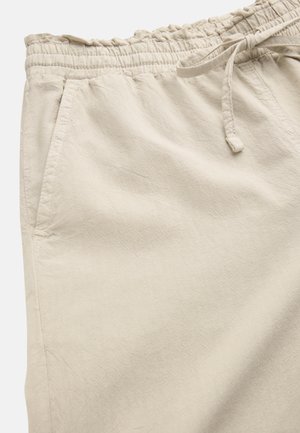 Beige afslappede bukser med elastisk talje og snøre, med sidelommer og letvægts stoftekstur.