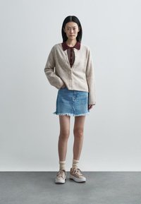 Bež kardigan, bordo srajca z ovratnikom, svetlo moder jeans krilo z rozgotanim robom, bež superge in krem nogavice. Preprost dizajn, sproščen kroj.