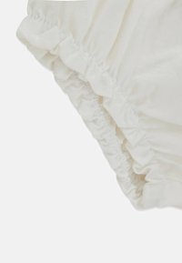 Weißer Stoff mit gerafften Rüschen entlang des Randes, glatter Textur und weichem Fall. Nahaufnahme hebt die Nähte hervor.