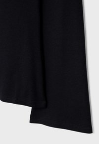 Črno rebrasto blago pada navzdol, s gladko teksturo in subtilnim raztezanjem. Robovi so zaključeni z enakomernim šivom.