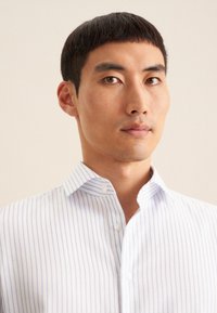 Shirt met blauwe en witte verticale strepen, met een kraag met knopen, gladde stof en een getailleerd ontwerp. Inclusief zichtbare knopen aan de voorkant.