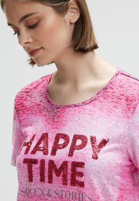 Pink short-sleeve shirt featuring a gradient design and sequined text "HAPPY TIME." Soft fabric with a round neckline and subtle texture details.