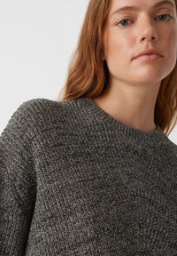 Gestrickter Pullover in Dunkelgrau mit strukturierter Oberfläche, rundem Ausschnitt und lockerer Passform. Das Material hat einen leichten Glanz, der visuelles Interesse weckt.