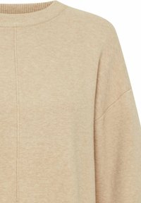 Pull en tricot beige avec un col rond côtelé et des épaules tombantes. Texture douce avec de subtils éclats et des détails de couture verticaux.