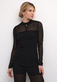 Schwarzes Spitzenoberteil mit langen Ärmeln, das einen hohen Kragen und ein Schlüsselloch-Detail aufweist, kombiniert mit passenden Spitzen-Shorts. Aufwendiges Blumenmuster über das gesamte Design.