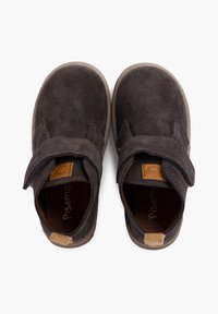 Scarpe scure in suede grigio con una fascia in Velcro, punta arrotondata e suola in gomma beige. Presenta un piccolo tag con logo sulla fascia.