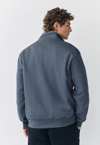 Antracietgrijze pullover sweater, met een hoge kraag, geribbelde manchetten en een gladde textuur, met een losse pasvorm.