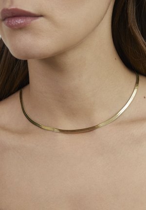 Collier ras-du-cou en métal doré avec un design lisse et épuré ; forme plate et flexible ; texture subtile ; épouse étroitement le cou.