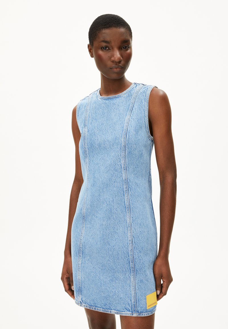 Denim jurk met een getailleerde silhouet, lichtblauwe kleur, mouwloos ontwerp, zichtbare stiksels en een klein geel label aan de zijkant.