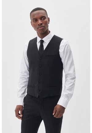 Gilet noir en tissu lisse, doté de six boutons, d'une poche passepoilée et d'une coupe ajustée, porté par-dessus une chemise blanche et une cravate noire.