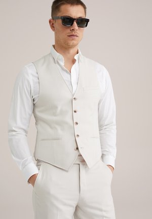 Light beige vest made of textured fabric, featuring a V-neck, five buttons, and a chest pocket, paired with a white shirt.