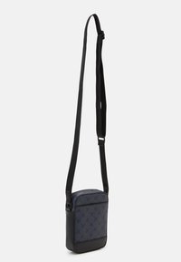 Borsa a tracolla blu navy realizzata in tessuto strutturato e pelle liscia. Presenta una tracolla nera regolabile, chiusura con zip e una sottile trama sul davanti.