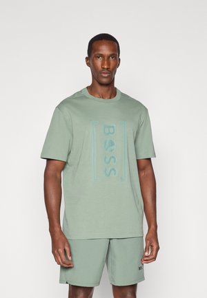 Mintgrøn bomulds T-shirt har et tonalt "BOSS" logo i midten. Modellen har matchende mintgrønne shorts på, begge med en glat tekstur.