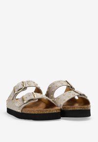 Sandalias de ante gris con dos correas ajustables, adornadas con tachuelas doradas y una plantilla de corcho sobre una suela de goma negra.