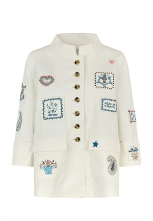 Witte jas met een hoge kraag, voorzien van diverse kleurrijke geborduurde badges, gouden knopen en twee grote voorzakken.