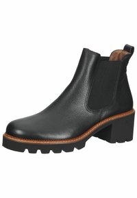 Botín de cuero negro hasta el tobillo con paneles laterales elásticos, parte superior texturizada, tacón grueso y suela de goma resistente con un ribete marrón en contraste.