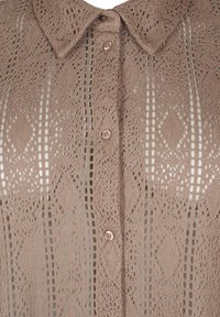 Beige kantblouse met een kraaghalslijn, voorzien van een knoopsluiting en ingewikkelde diamant- en streepjespatronen door het geheel.
