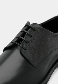 Czarne skórzane buty z teksturowanym czarnym panelem, wyposażone w sześć oczek na sznurowadła. Gładkie wykończenie i elegancki design.