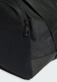 Mochila negra con un bolsillo lateral de malla texturizada y fabricada con un tejido sintético duradero, con un acabado suave y correas reforzadas.