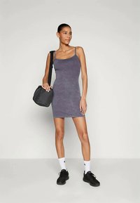 Violet prigludusi be rankovių suknelė su švelnia tekstūra, derinama su juoda rankine ir juodais sportbačiais, dėvima su baltais kojiniais. Paprastas dizainas.