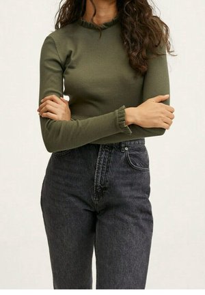 Top de manga larga acanalado en verde oliva con un escote con volantes, combinado con jeans negros de mezclilla de cintura alta. El material es elástico y ajustado.