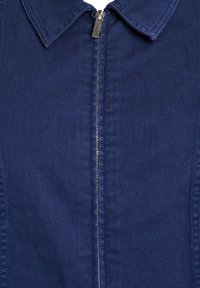 Tamnoplavi zip-up jakna s ovratnikom, izrađena od glatkog materijala. Ima središnji patent zatvarač i čiste šavove, pružajući strukturirani izgled.