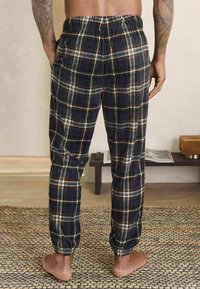 Nachtwäsche-Hosen aus Flanell in Marineblau mit cremefarbenem und rostfarbener Karomuster, elastischem Bund, schmal zulaufenden Beinen und einer weichen Textur.