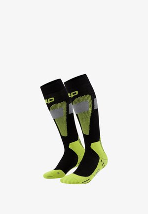 Schwarz und neon-grüne knielange Socken mit strukturierten Einsätzen, verstärkter Zehen- und Fersenpartie. Mit grauen Akzenten und geripptem oberen Bündchen.