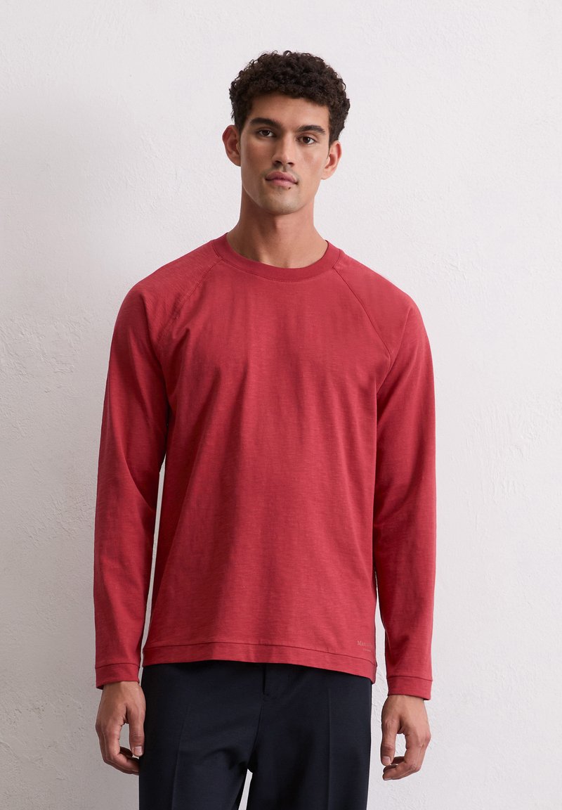 Lange mouwen rode shirt gemaakt van lichte stof met een ronde halslijn en raglan mouwen, met een subtiele textuur en een rechte zoom.