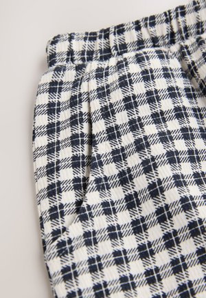 Tissu à carreaux blanc et marine avec une ceinture élastique froncée, présentant un tissage texturé et un motif en grille uniforme.