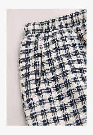 Tessuto a quadretti bianchi e blu navy con vita elasticizzata arricciata, caratterizzato da una trama testurizzata e un motivo a griglia regolare.
