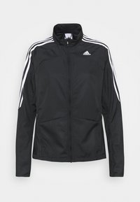 Chaqueta deportiva negra con rayas blancas en las mangas, frontal con cremallera y dos bolsillos laterales. Fabricada con material ligero y texturizado.