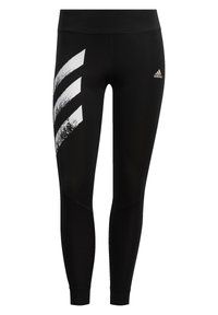 Czarne legginsy wykonane z elastycznego materiału, z białym graficznym wzorem trzech skośnych pasków po lewej stronie oraz logo Adidas na talii.