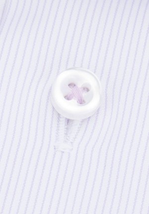 Biały guzik z czterema dziurkami, przyszyty jasnofioletową nitką, na tle jasnofioletowej w paski tkaniny.