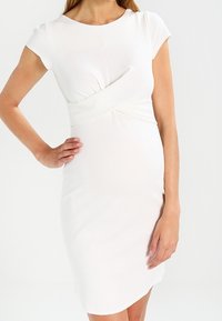 Weißes Kleid mit kurzen Ärmeln, figurbetontem Design, geraffter Textur an der Taille und knielangem Saum. Weicher, glatter Stoff.