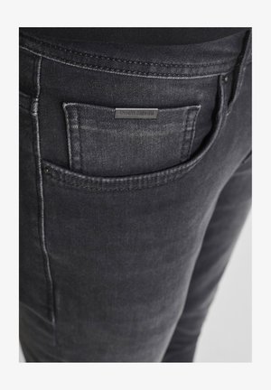 Jeans in denim nero con una leggera finitura sbiadita, dotati di una tasca posteriore e di una piccola etichetta del marchio. Dettagli cuciti lungo le cuciture.