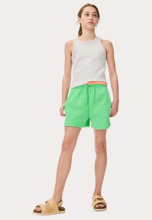 Gray sleeveless top layered over a bright green pair of shorts with an elastic waistband, worn with tan slide sandals.