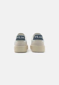 Witte en grijze leren sneakers met een beige rubberen zool. Bevat een blauwe suede hielcounter met het "VEJA" logo. Minimalistisch ontwerp.