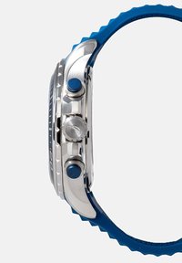 Hõbedane metallist kell sinise silikoonrihmaga, roostevabast terasest korpus, sinised aktsendid nupudel ja tekstureeritud pind.