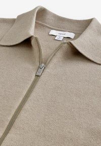 Beige Zip-up-Pullover aus strukturiertem Strickstoff mit klassischem Kragen und metallic Reißverschluss. Das Etikett weist die Größe M aus.