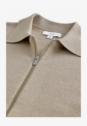 Beige Zip-up-Pullover aus strukturiertem Strickstoff mit klassischem Kragen und metallic Reißverschluss. Das Etikett weist die Größe M aus.