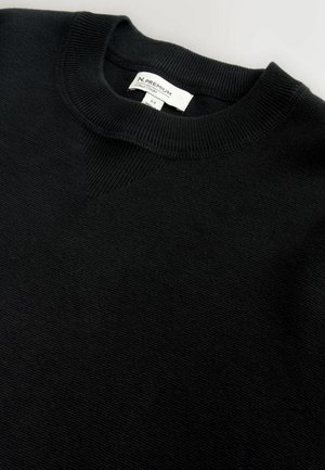 Pull en maille noir avec un col rond côtelé et un subtil accent en forme de V. Présente un tissu texturé et une étiquette de marque visible à l'intérieur.