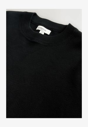 Pull en maille noir avec un col rond côtelé et un subtil accent en forme de V. Présente un tissu texturé et une étiquette de marque visible à l'intérieur.