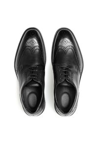 Chaussures habillées en cuir noir présentant un design brogue avec un bout poli, une surface lisse et des perforations détaillées le long des bords.