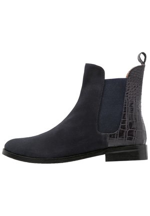 Bottine Chelsea en daim noir avec panneau latéral élastique et motif crocodile texturé sur le talon, talon bas empilé et languette de traction à l'arrière.