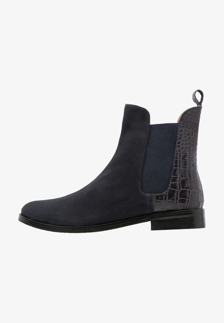 Bottine Chelsea en daim noir avec panneau latéral élastique et motif crocodile texturé sur le talon, talon bas empilé et languette de traction à l'arrière.