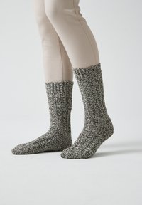 Calze lavorate a maglia in un motivo melangiato grigio e bianco, con una texture a coste e un design lungo fino al polpaccio. Materiale morbido ed elastico.