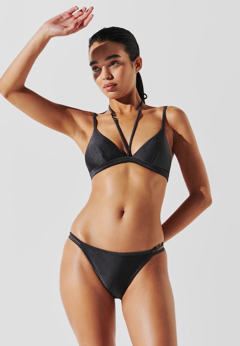 Fekete bikini szett, háromszög alakú melltartóval és alacsony derekú alsóval. Az anyag textúrált, enyhe fényes felülettel. Vékony, állítható pántokkal rendelkezik.
