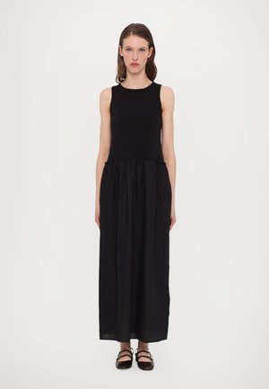 Zwarte maxi-jurk met mouwloze top, slanke lijfje en geraffineerde rok. Gemaakt van lichtgewicht stof met een gladde textuur. Platte, strapless schoenen.