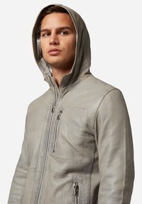 Leren hoodie-jack in lichtgrijs. Beschikt over een rits aan de voorkant, twee met rits afgesloten zakken en een zachte textuur met duidelijke naden.